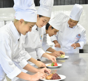 Professional chef happily teaching students the art of cuisine in Faculty of Tourism and Hospitality Industry.
